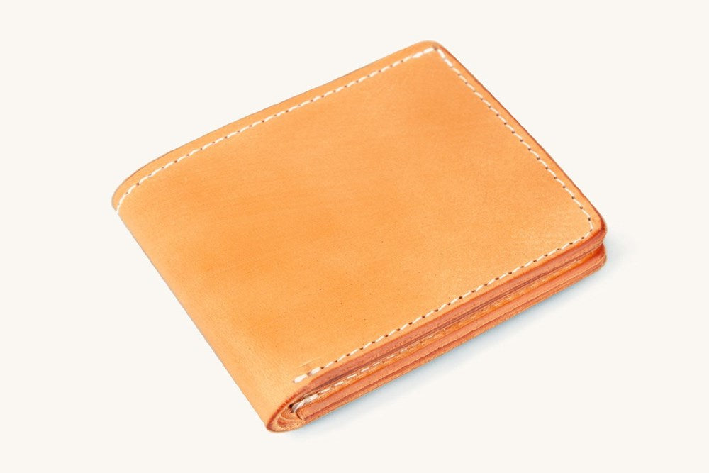 Golden Utility Bifold wallet of smooth leather, closed and angled, with white stitching.