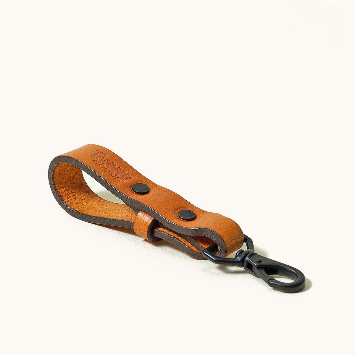 Saddle tan leather Key Lanyard with black hardware and rivets, angled on a white background.