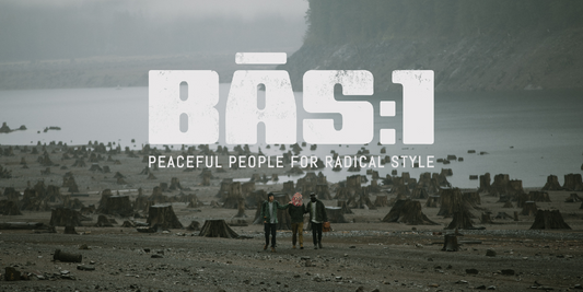 Three friends walk arm-in-arm across a misty, tree-stump-strewn shoreline, embodying BAS:1’s radical style with peaceful intent.