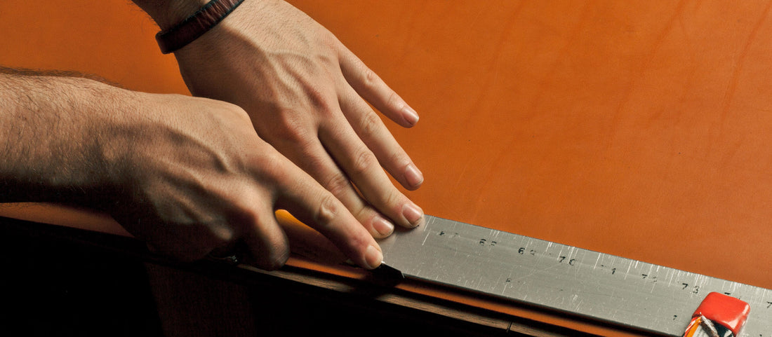 Hands measuring and marking leather with ruler and knife during belt crafting workshop.