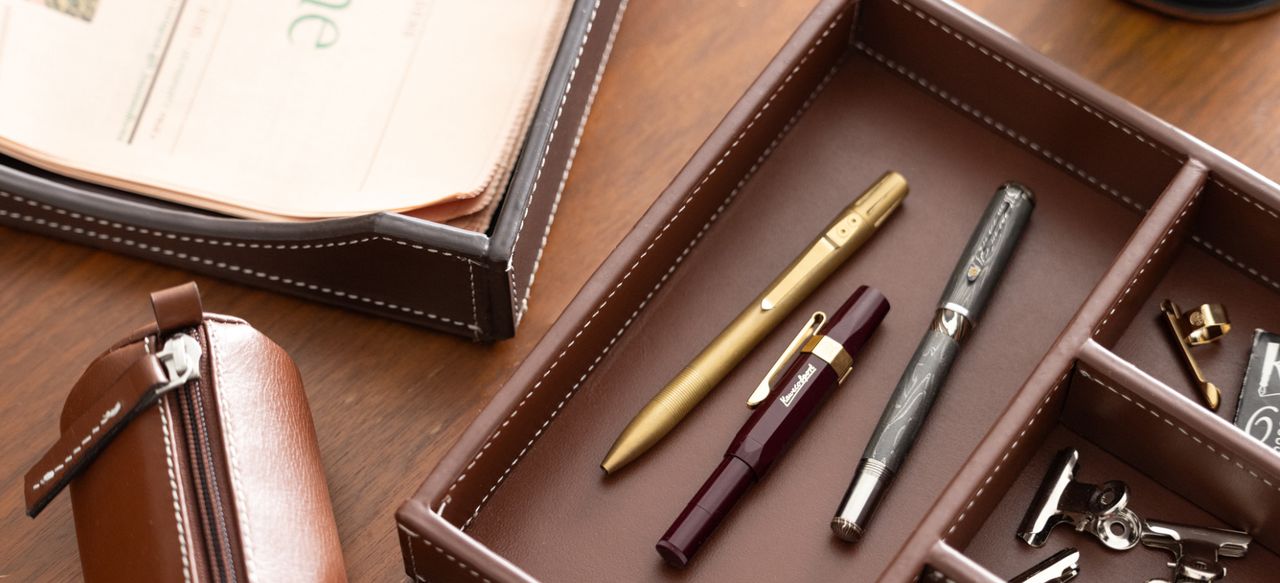 Elegant office essentials in rich browns and metallics—luxury pens, leather organizer, and refined accessories for the sophisticated professional.