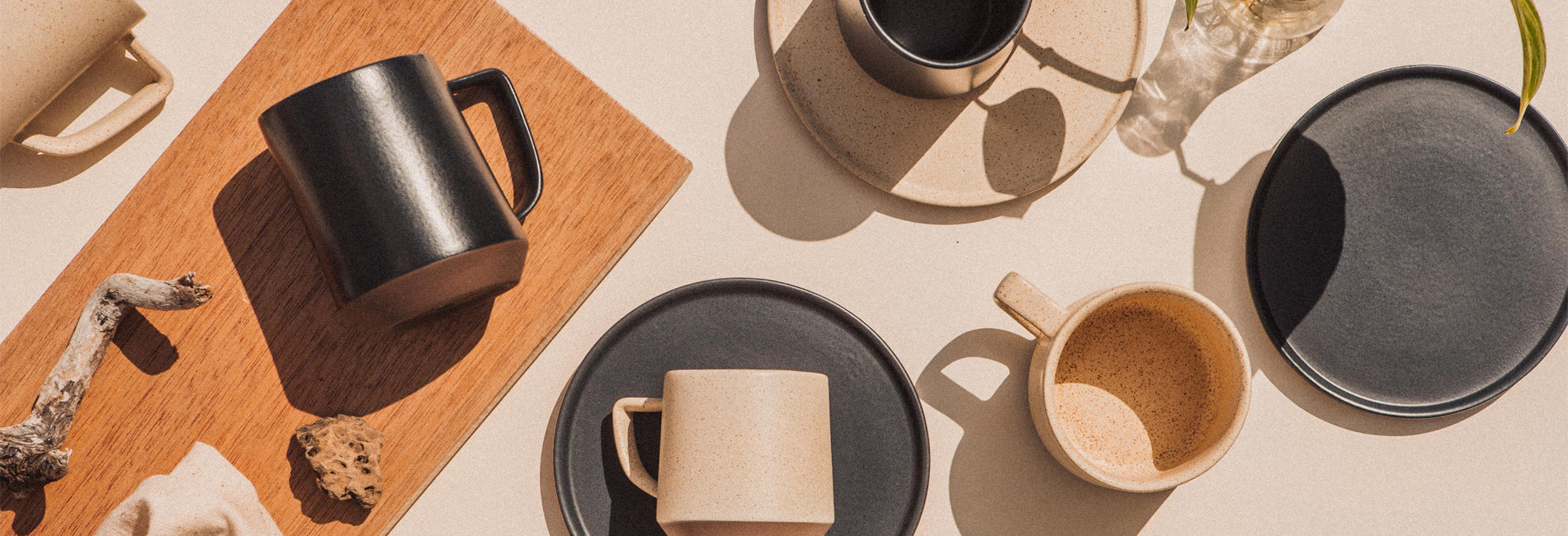 Elegant ceramic mugs and plates in neutral tones, styled with wood and natural elements for a minimalist, cozy lifestyle.