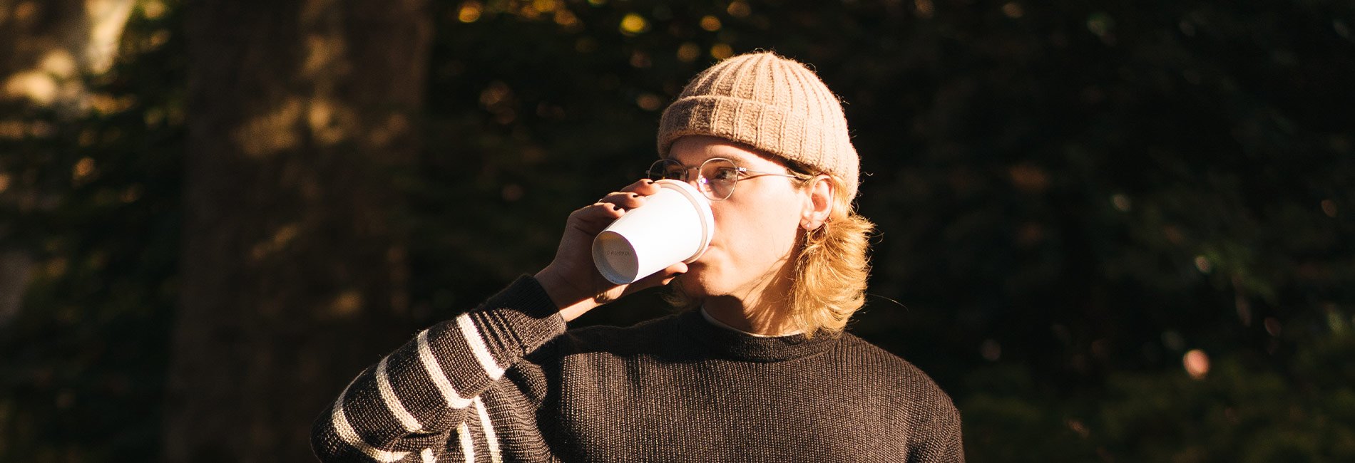 Cozy autumn apparel: striped sweater, beige beanie, warm tones, relaxed outdoor lifestyle.