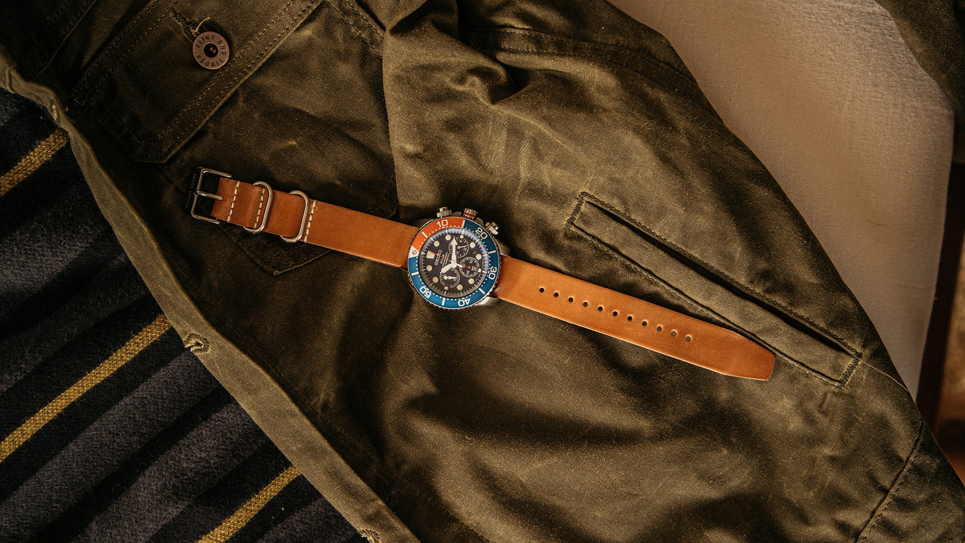wristwatch lying on a green canvas coat