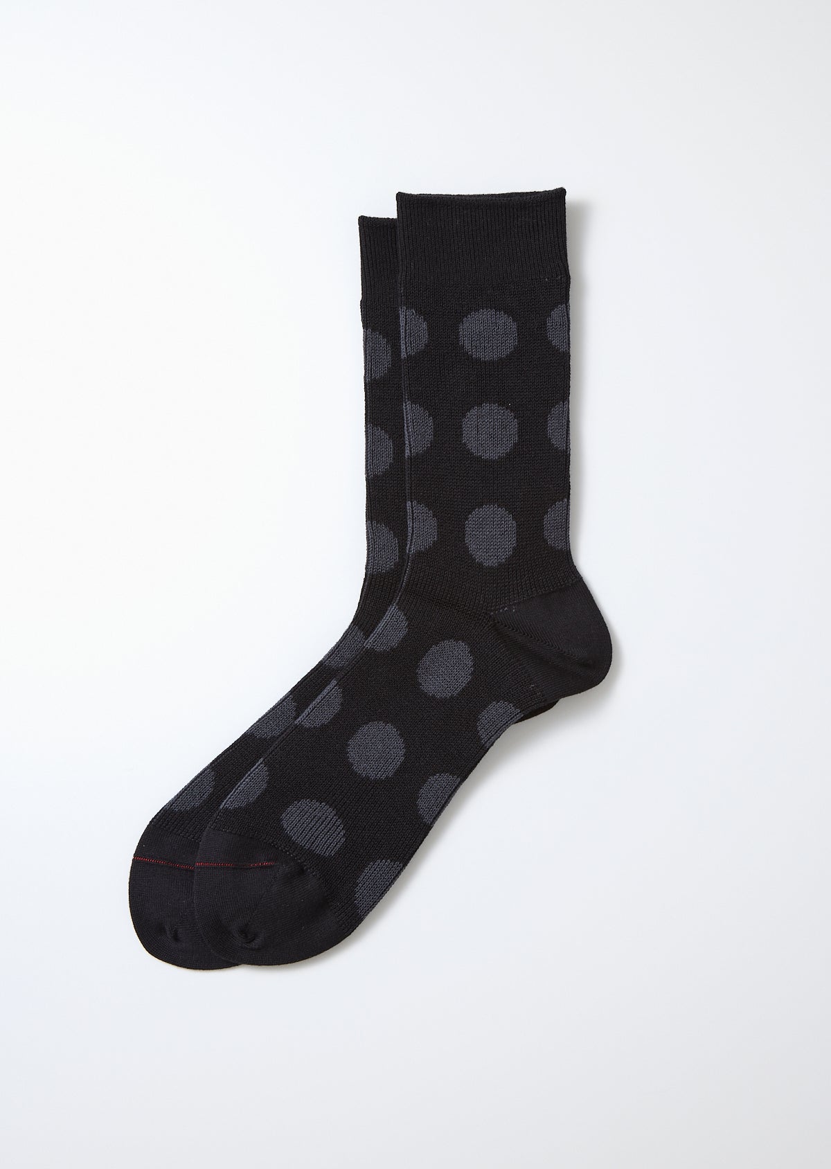 Black and charcoal polka dot socks laid flat, featuring a ribbed cuff and smooth knit texture.