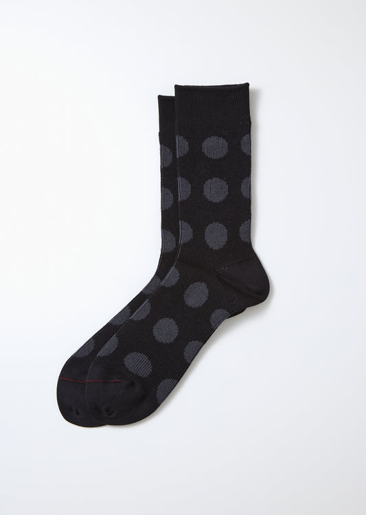 Black and charcoal polka dot socks laid flat, featuring a ribbed cuff and smooth knit texture.