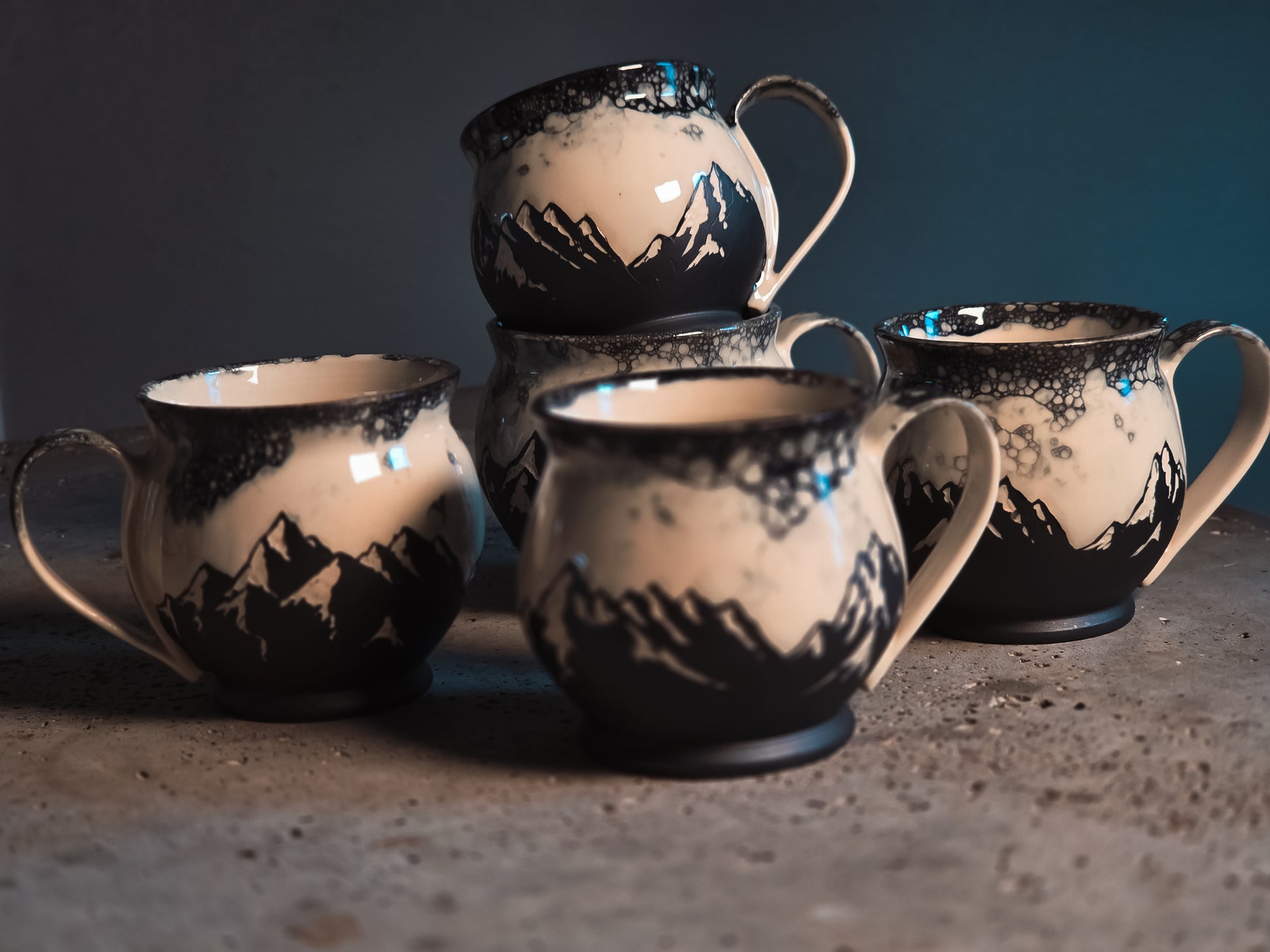 Ceramic Bubble Mountains mug with black mountain silhouettes and white bubble glaze, displayed in a group.