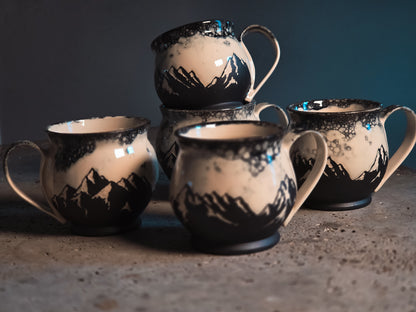 Ceramic Bubble Mountains mug with black mountain silhouettes and white bubble glaze, displayed in a group.