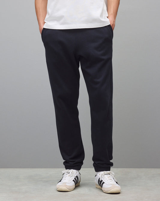 Dark navy sweatpants with a relaxed fit and cuffed ankles, styled with a white t-shirt and white sneakers.