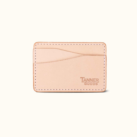 Natural leather money clip wallet by Tanner Goods with visible white stitching and debossed logo.