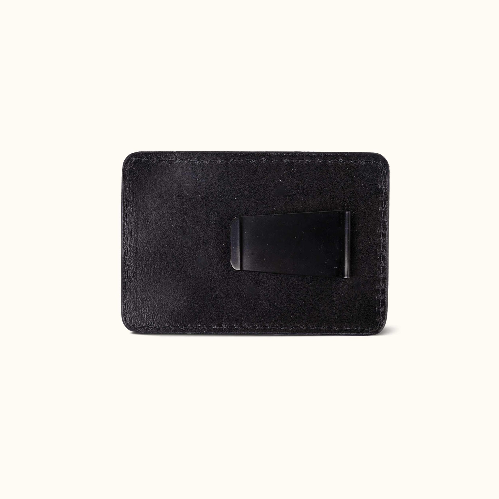 Black leather money clip with visible stitching and a black metal clip.