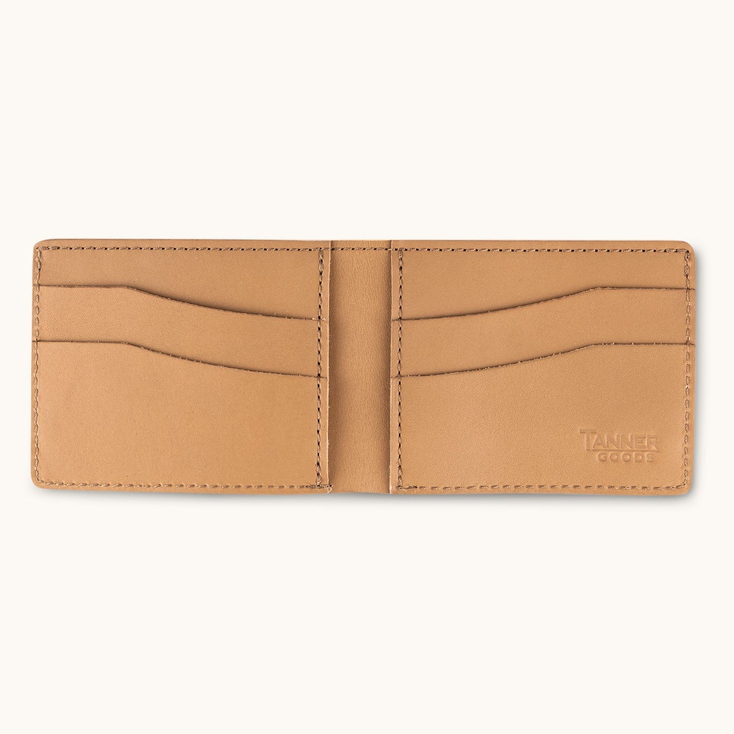 Light brown leather bifold wallet by Tanner Goods, open to show card slots and embossed logo.