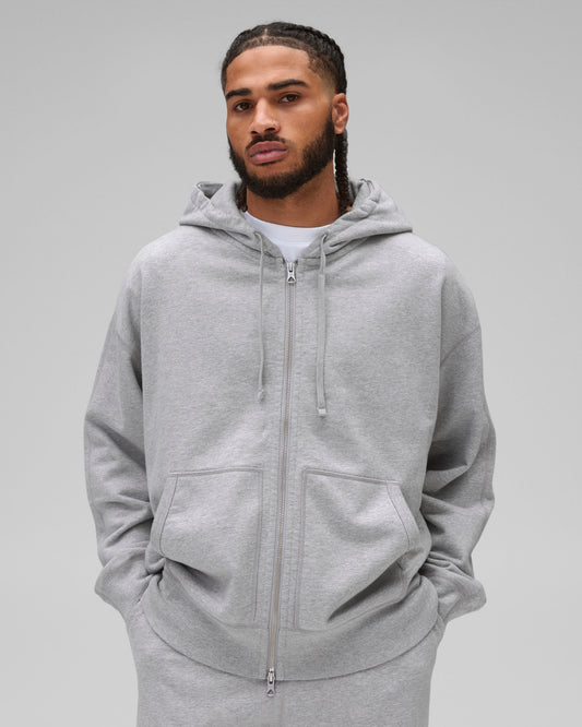 Grey Midweight Terry Relaxed Zip Hoodie with a full zipper, drawstrings, and front pockets, worn by a male model.