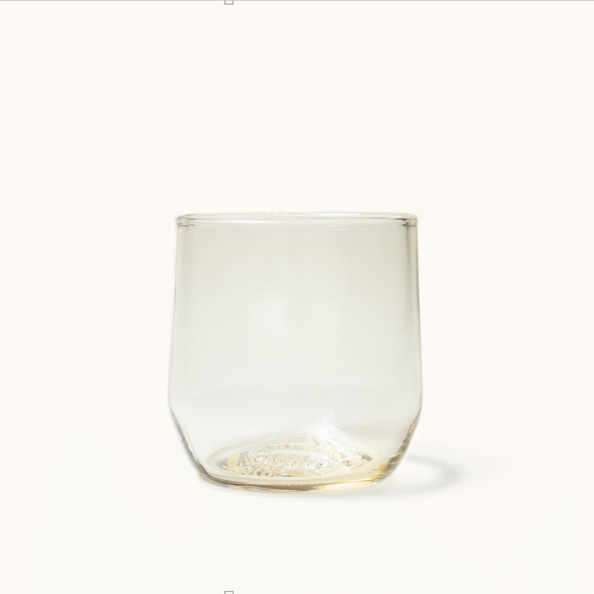 Clear stemless cocktail glass with a warm amber tint and an embossed, textured pattern on the base.