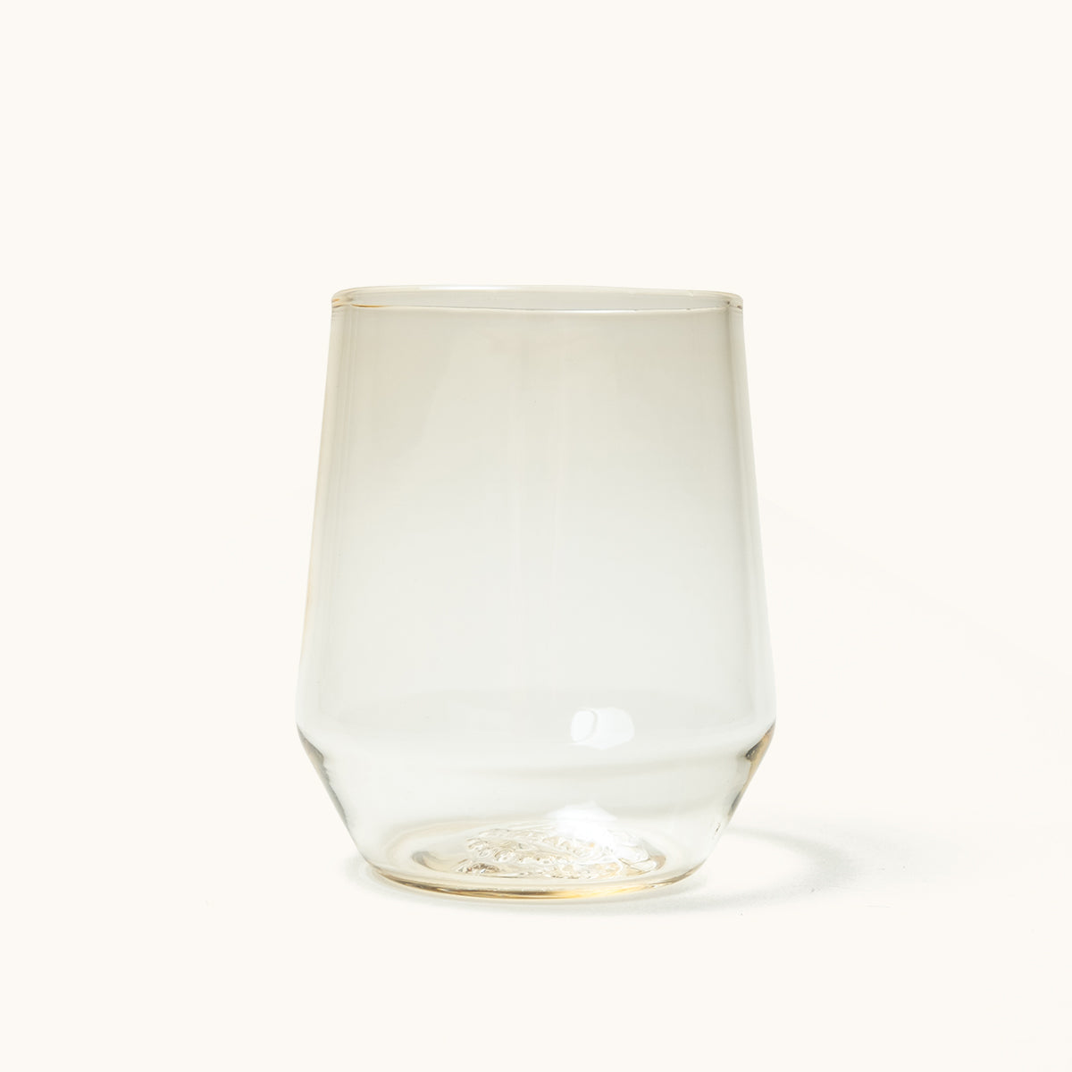 Stemless wine glass with a slight amber tint, featuring textured detail on the clear glass base.