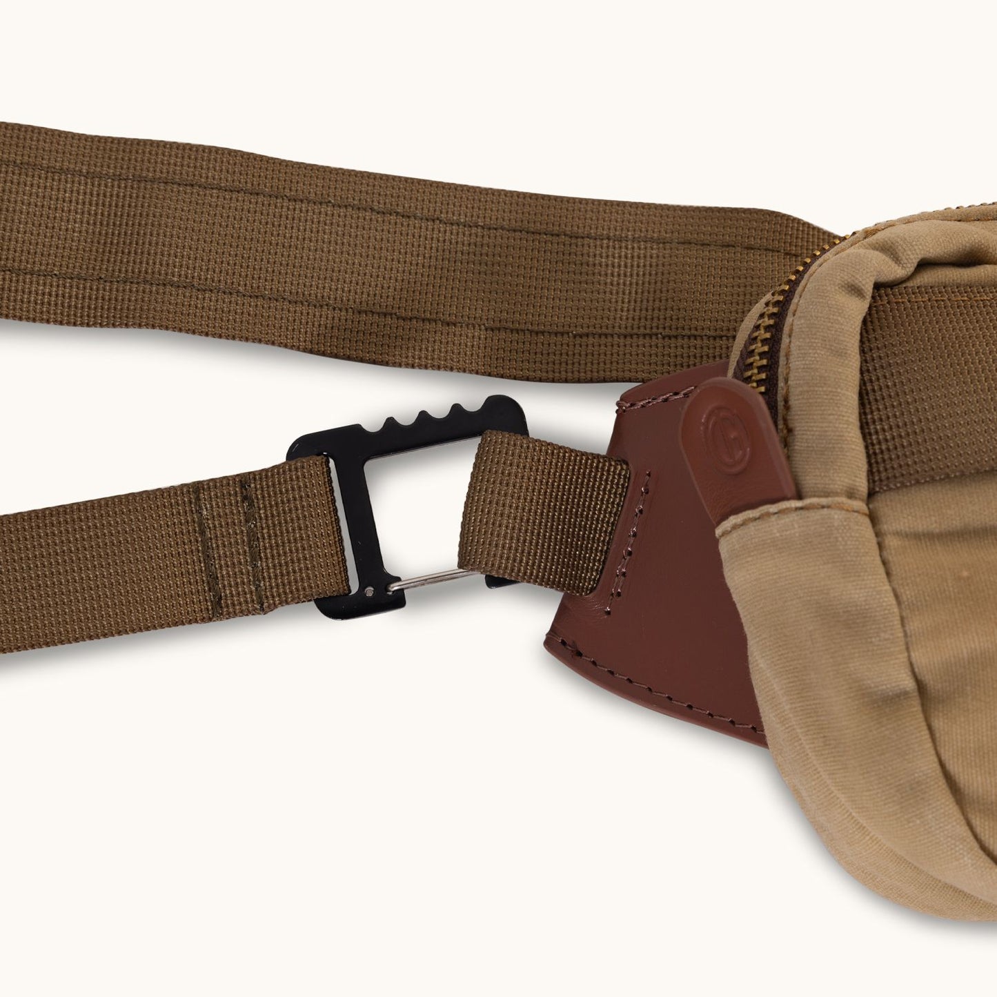 Utility Tan Waxed Canvas Crossbody Mini with a brown woven strap, black buckle, and brown leather accent, shown in a close-up.