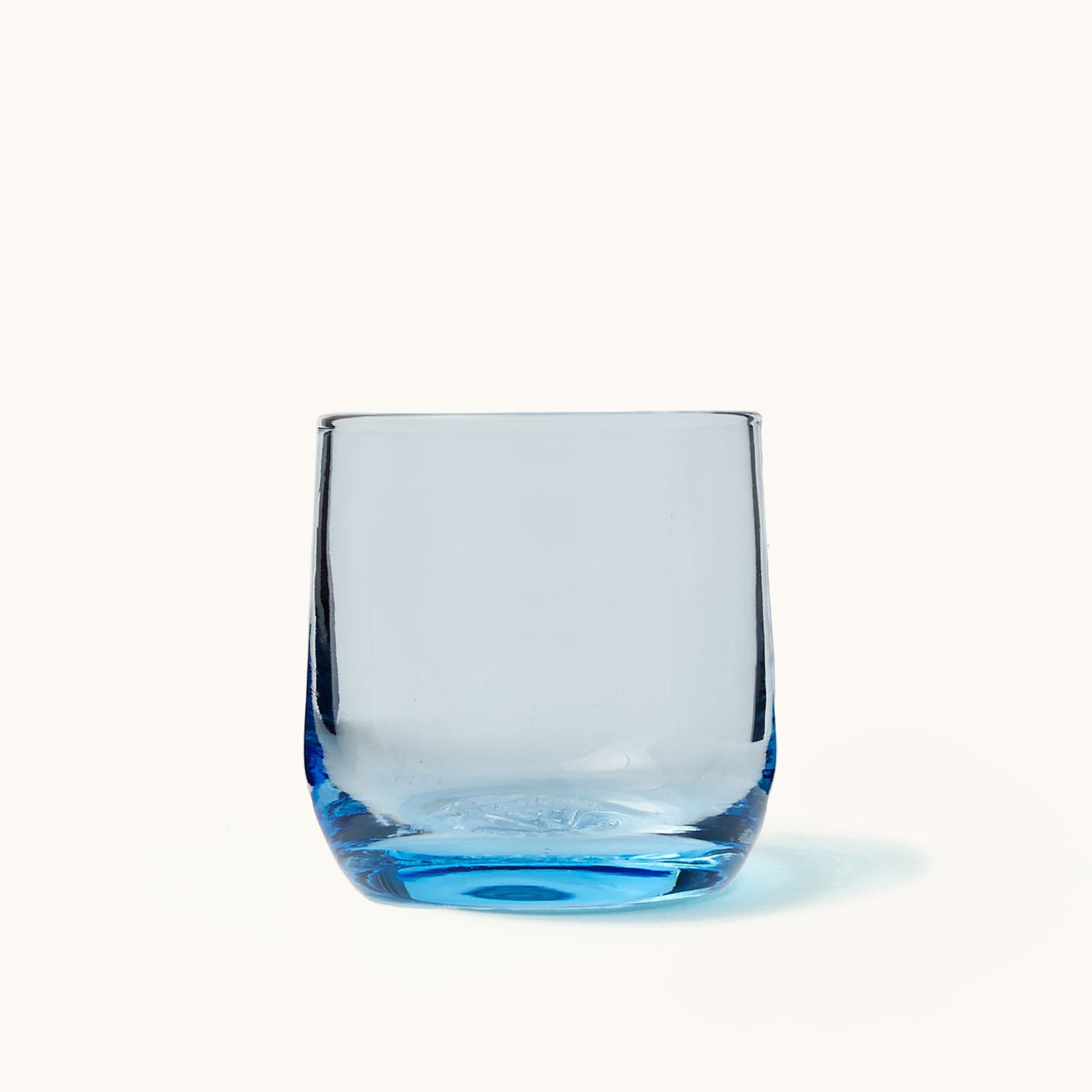 Clear cocktail glass with vibrant blue base, thick rim, and rounded shape, front view on white background