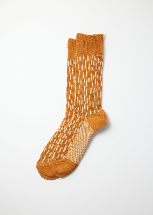 Pair of mustard yellow crew socks with an off-white dash pattern and a mesh knit foot detail.