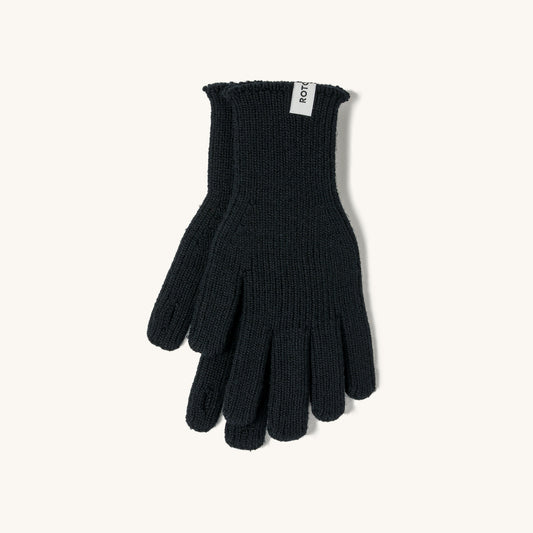 Black merino knit touch gloves with ribbed cuffs and a white brand tag, laid flat on a cream background.