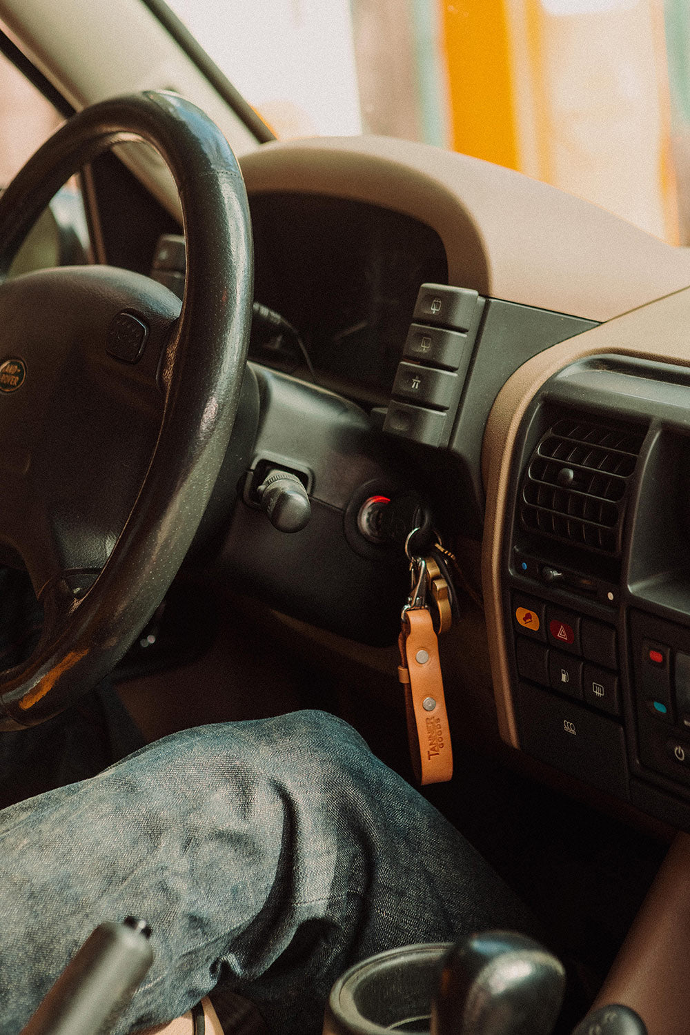 Saddle tan leather key lanyard with keys, hanging in a car's ignition.