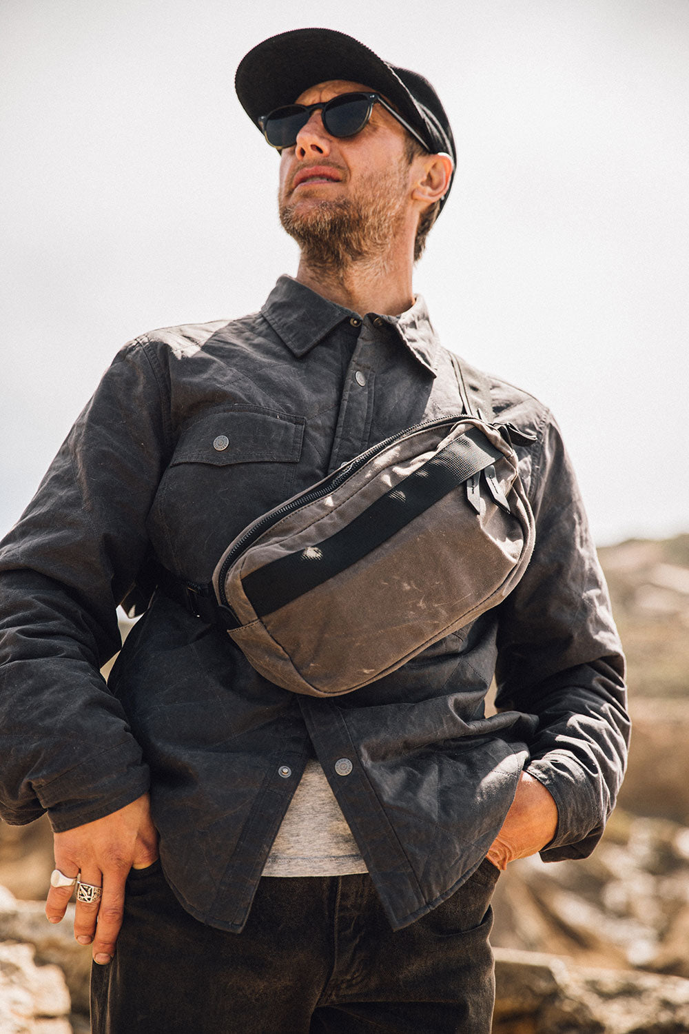 Slate Grey Waxed Canvas Canyon Crossbody Pack worn across a man's chest, with a black zipper and strap.