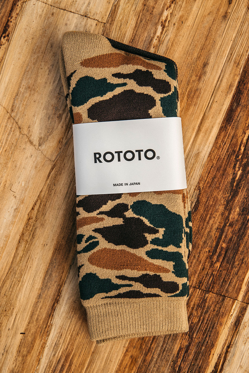 Khaki Pile Crew Socks by ROTOTO featuring a camouflage pattern and ribbed cuffs, packaged on wood.