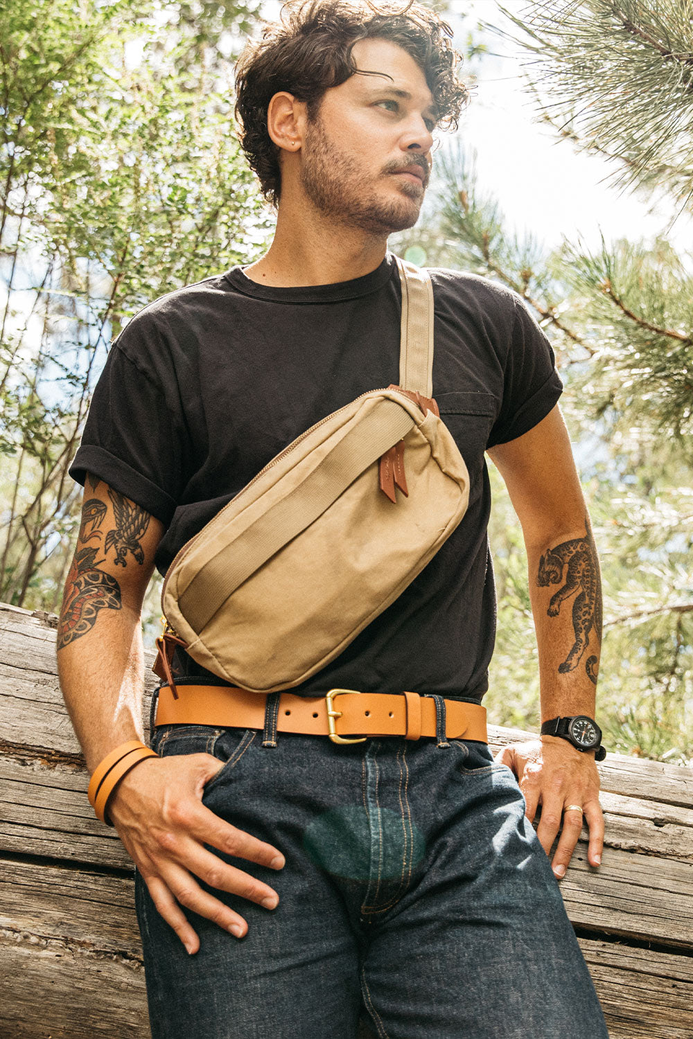 Saddle tan leather belt with a brass-toned buckle worn by a man in dark wash jeans.