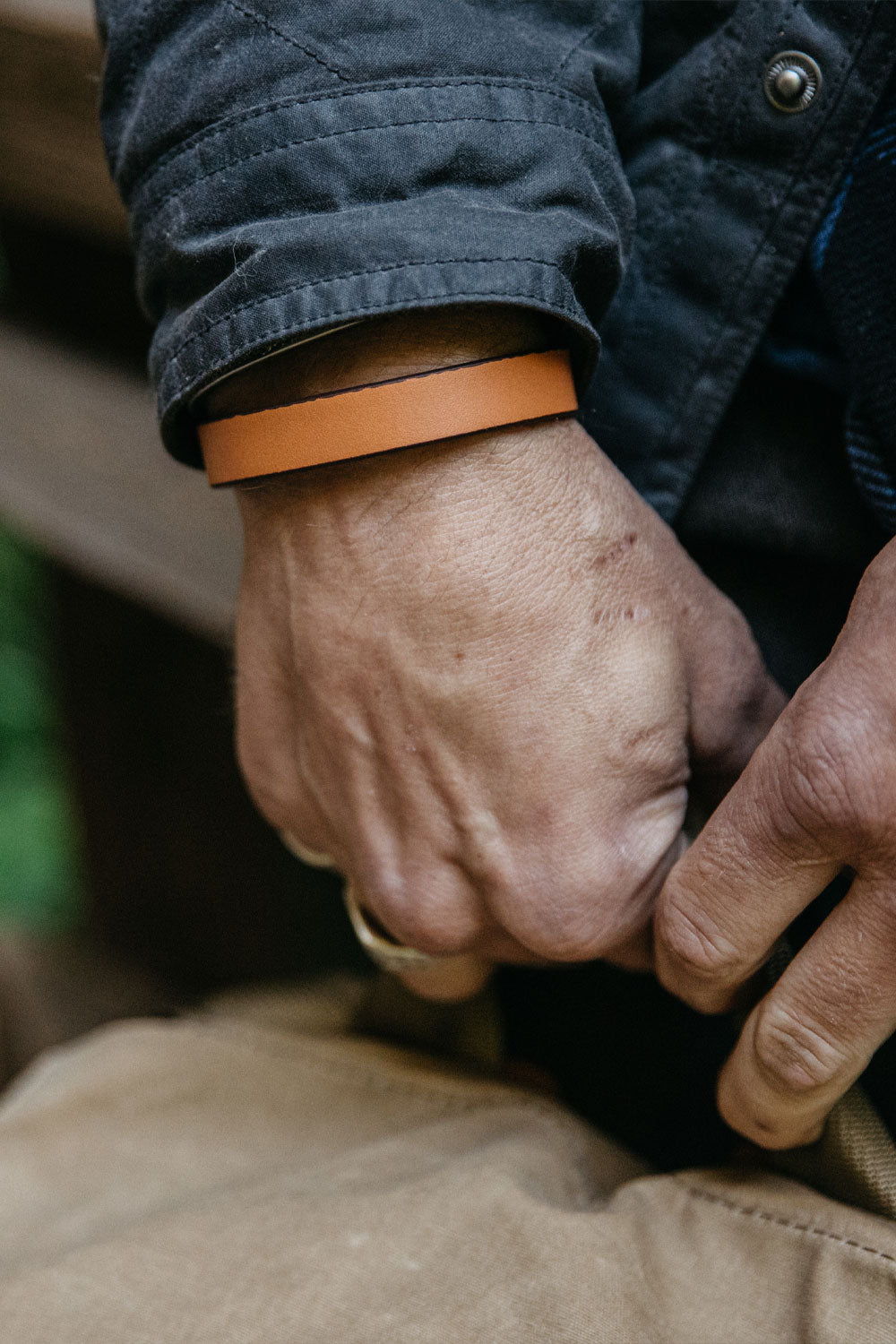 Saddle tan single wrap wristband on a man's wrist, styled with a dark grey jacket.