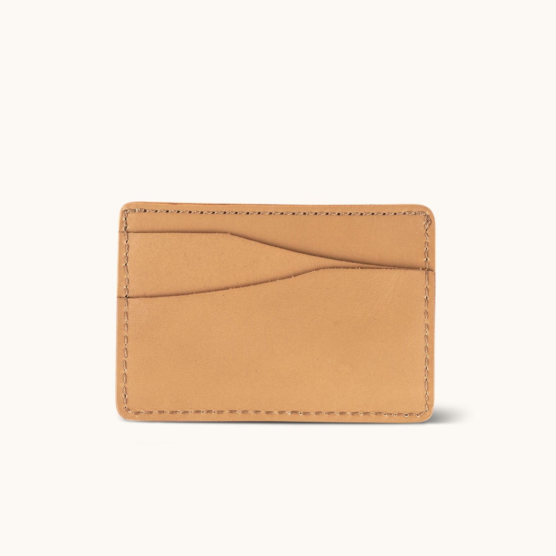 Light brown leather wallet with two curved card slots and visible perimeter stitching.