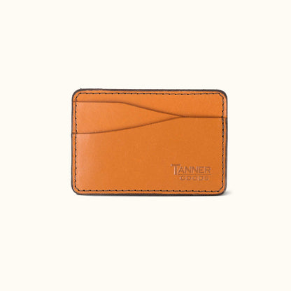 Saddle tan leather money clip by TANNER GOODS with black stitching, multiple card slots, and embossed logo.