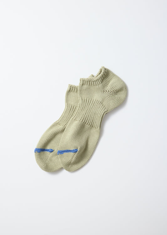 A pair of light khaki chunky sneaker socks with blue stripes on the toes, knitted and laid flat.