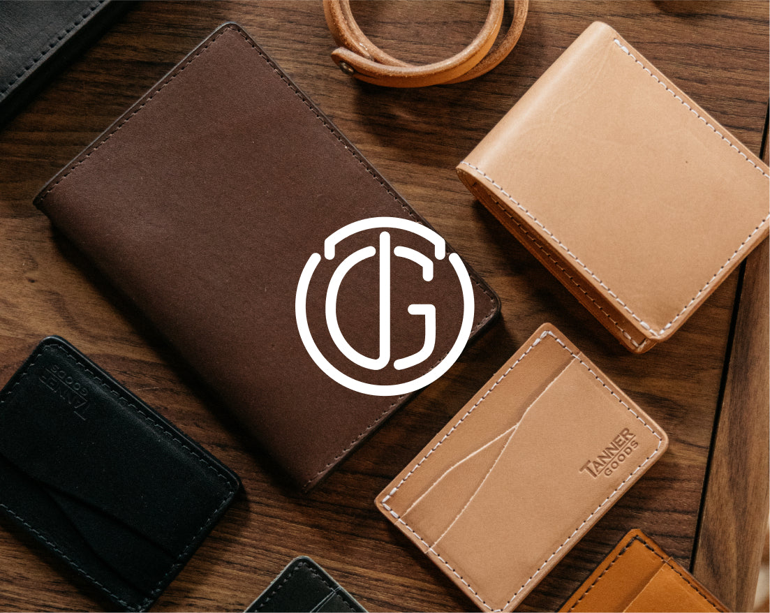 Brown and tan leather wallets with white stitching on wooden surface, featuring "TANNER GOODS" branding and a white circular logo overlay.