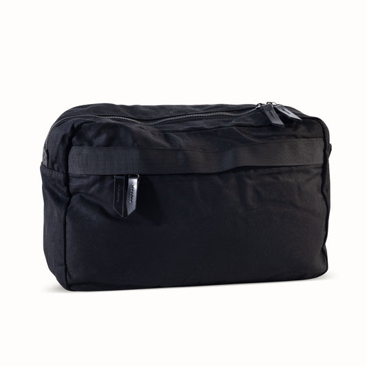 Large black waxed canvas crossbody bag featuring a main zipper and a horizontal front webbing strap.