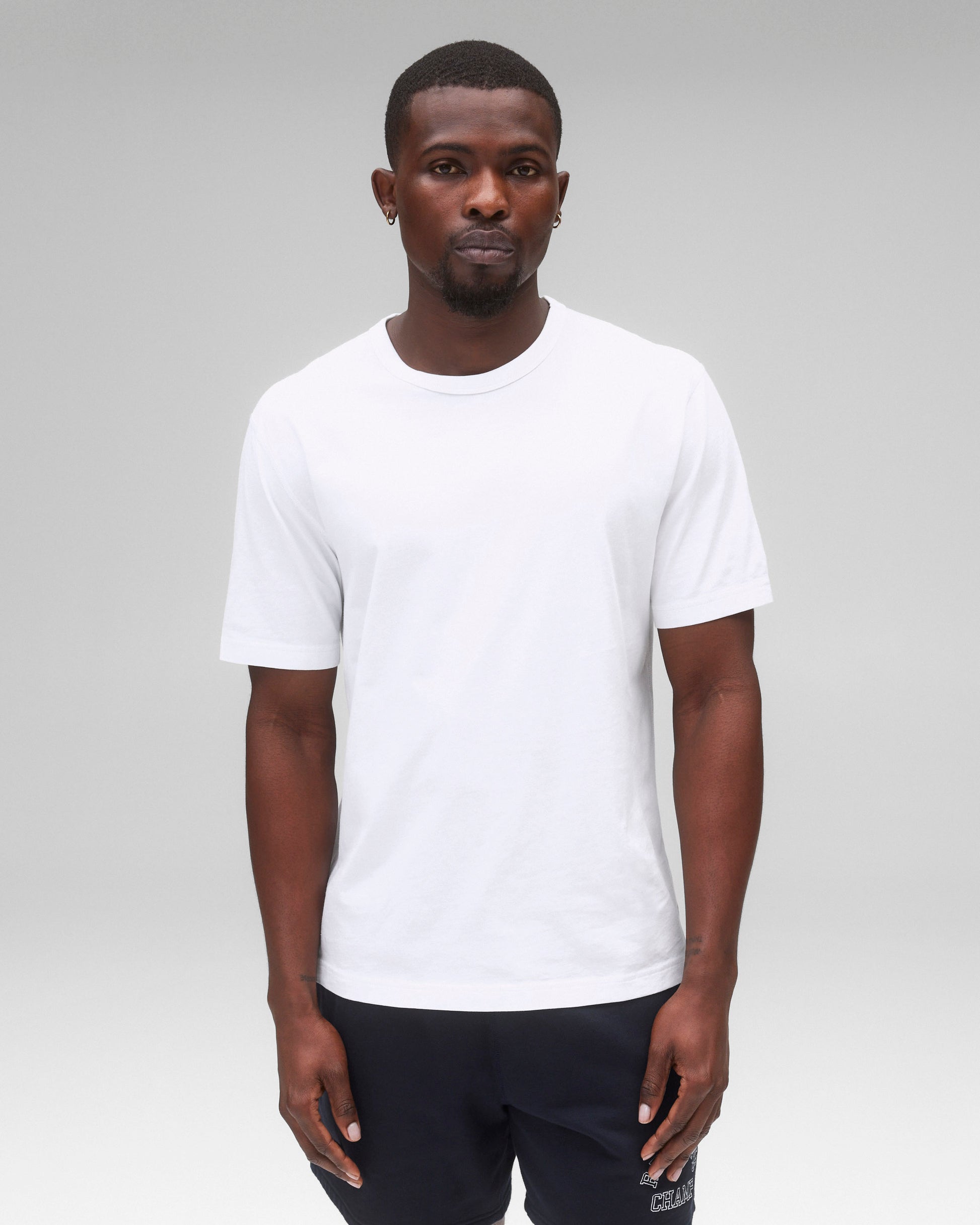 White lightweight jersey t-shirt with a crew neck and short sleeves, worn by a male model with dark shorts.