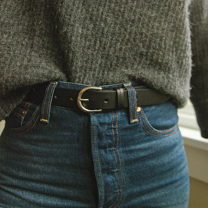 Black leather Meridian belt with a silver buckle, styled with blue jeans and a fuzzy grey sweater.
