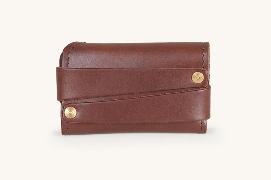 Cognac leather cardholder featuring two horizontal straps with brass snaps, front view.