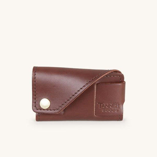 Dark brown leather cardholder by Tanner Goods with a snap button closure and embossed logo.