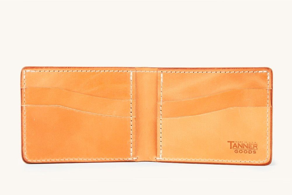 Golden leather bifold wallet by Tanner Goods, open to show multiple card slots and white stitching.