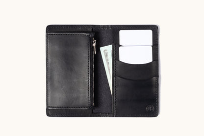 Black leather bifold wallet open to show card slots with two white cards, a zippered pocket, and a dollar bill.
