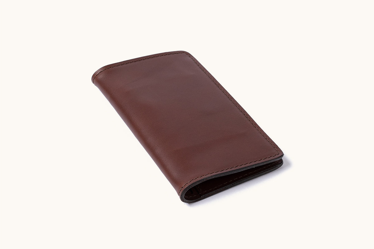 Cognac leather bifold wallet with stitched edges, shown at an angle on a white background.