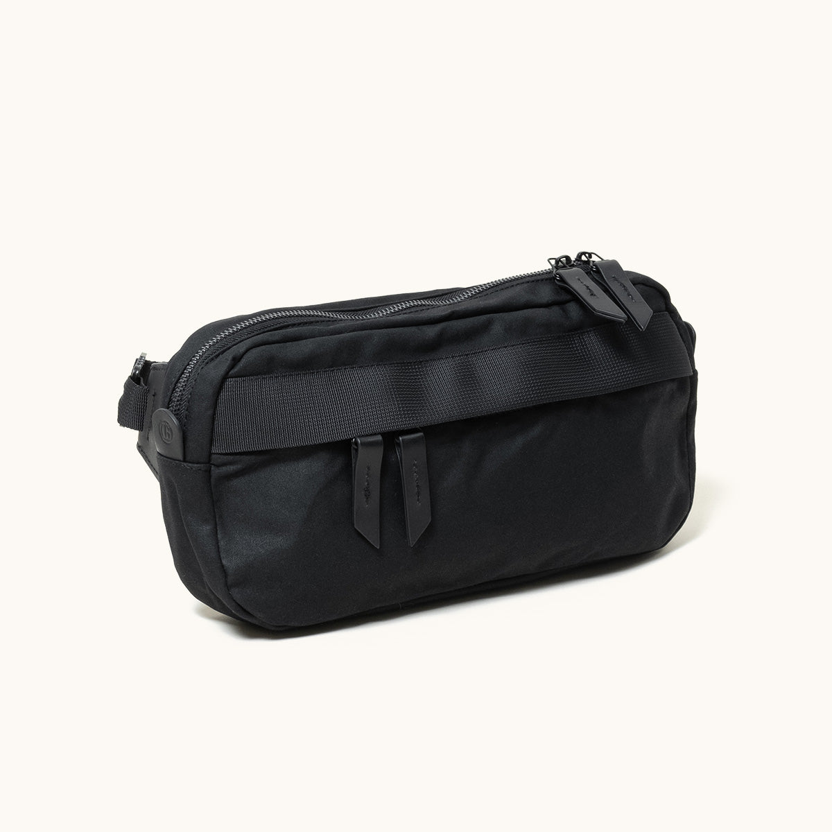 Black fabric crossbody bag in an angled view, with multiple zippered compartments and black zipper pulls.