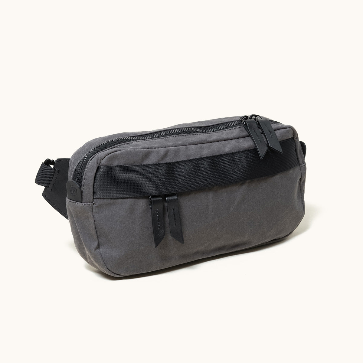 Dark grey fabric Canyon Crossbody bag with a black front strap and two zipper pulls, angled view.