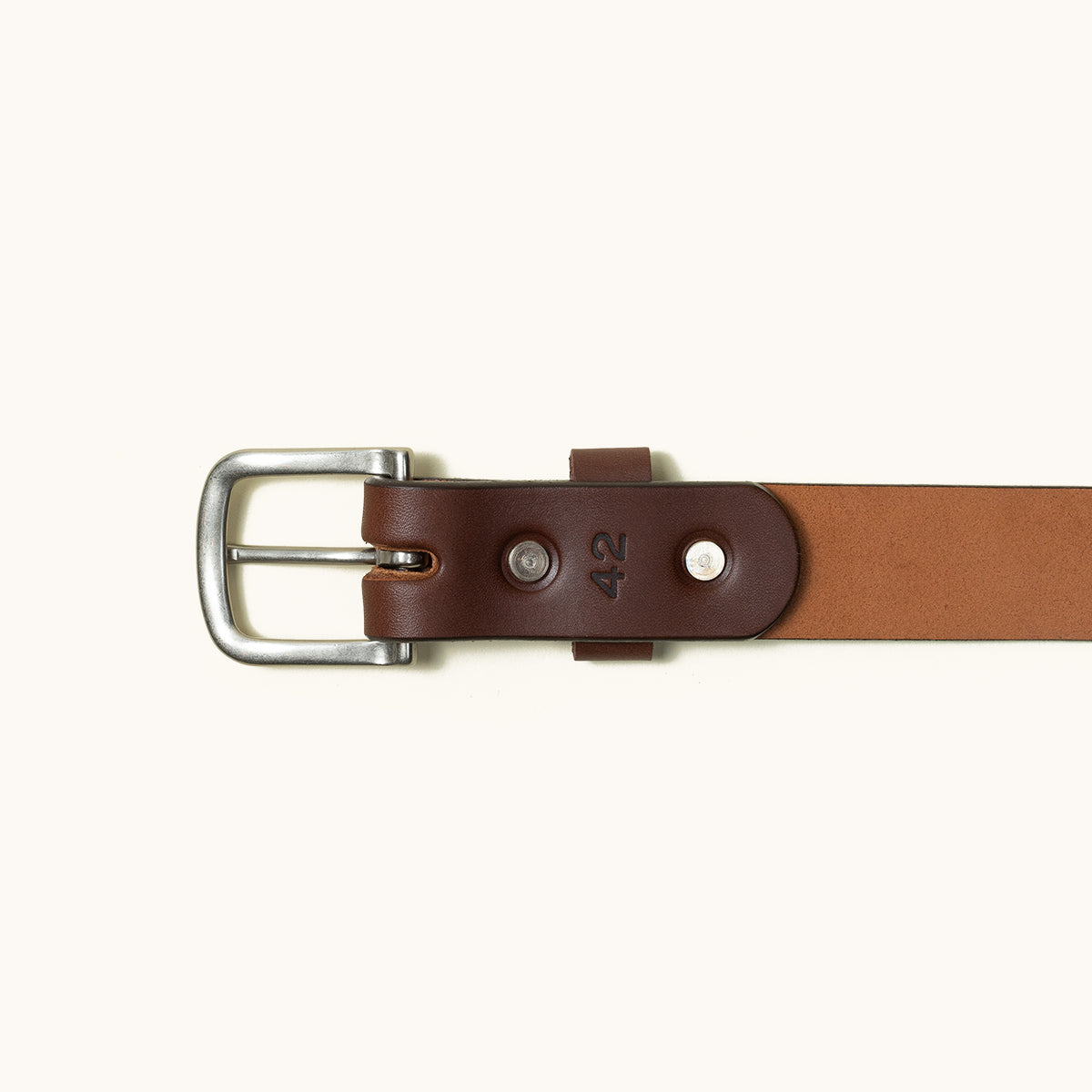 Cognac leather belt with a silver-toned square buckle and the number 42 stamped on the leather.