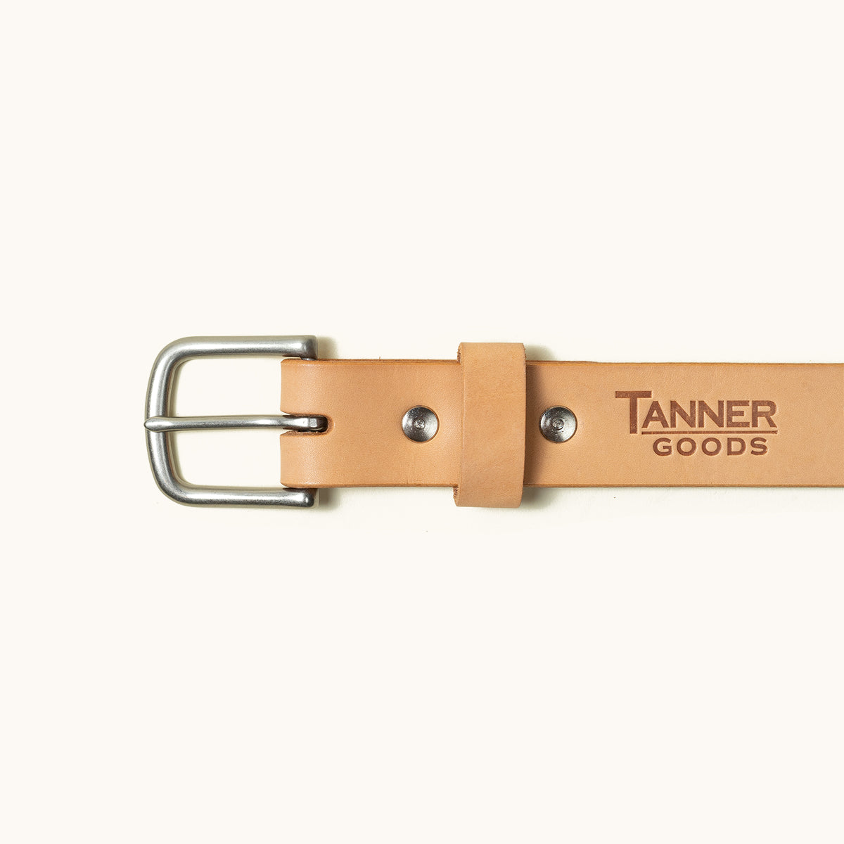 Natural leather classic belt by Tanner Goods with a silver buckle and embossed logo.
