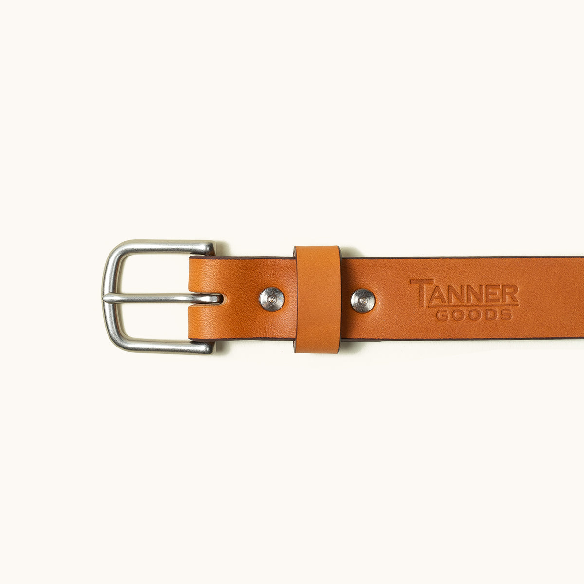 Tan leather belt with a silver buckle, featuring two rivets and embossed lettering.