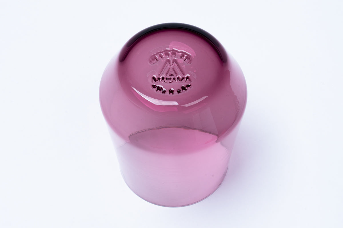Dark purple cocktail glass fading to light pink, with an embossed MAZANA logo and text on its base.