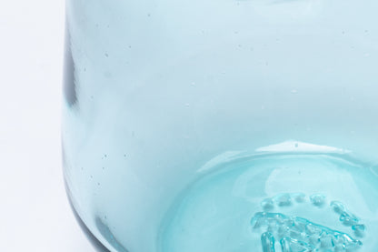 Light blue 16oz standard pint glass with small bubbles and a textured bottom.