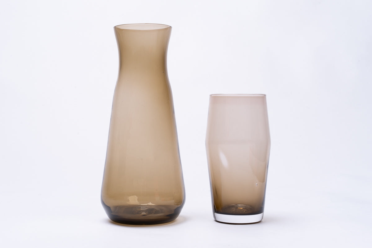 Smoky brown glass pint with a white base, displayed next to a taller matching carafe.