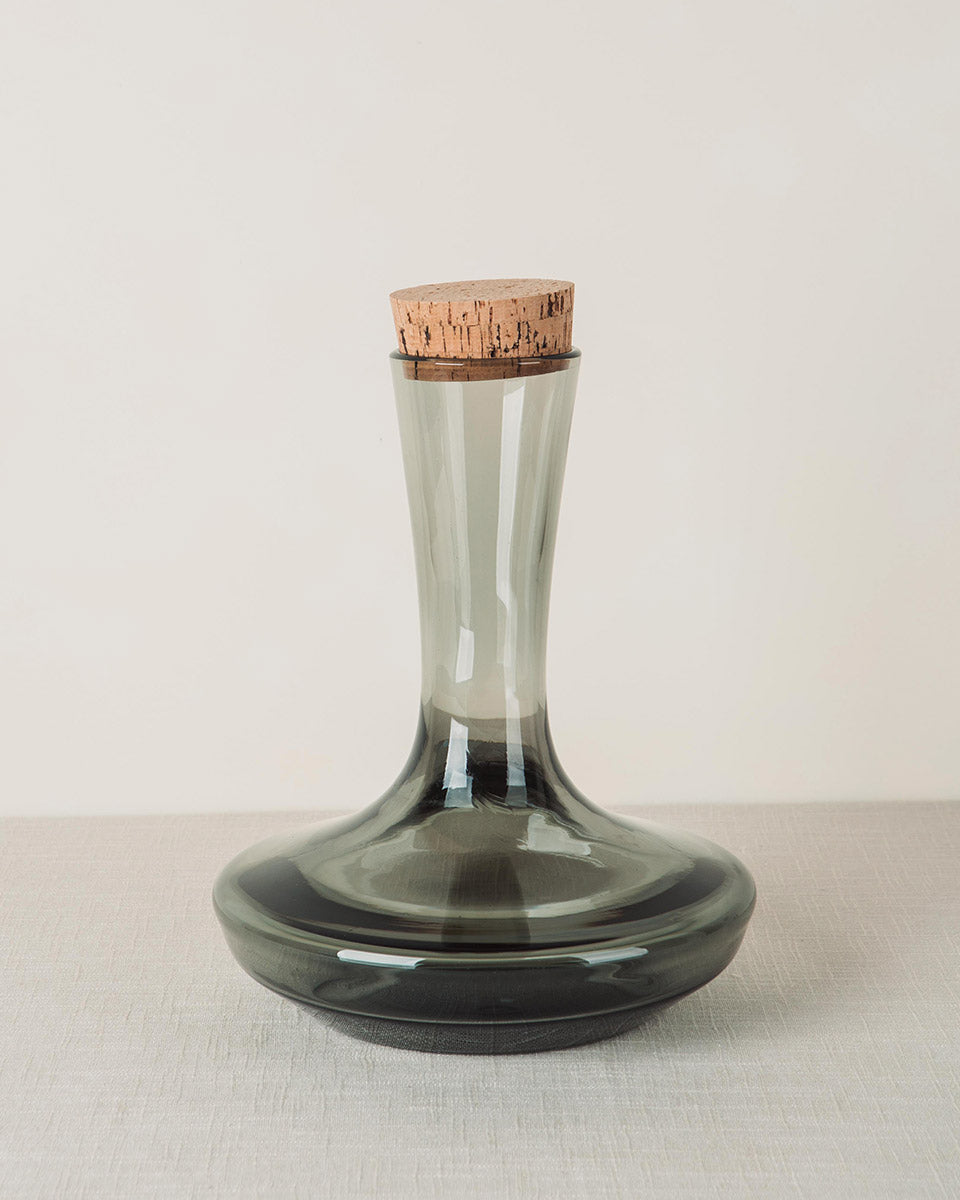 Dark grey glass decanter with a tall tapered neck, wide base, and cork stopper.
