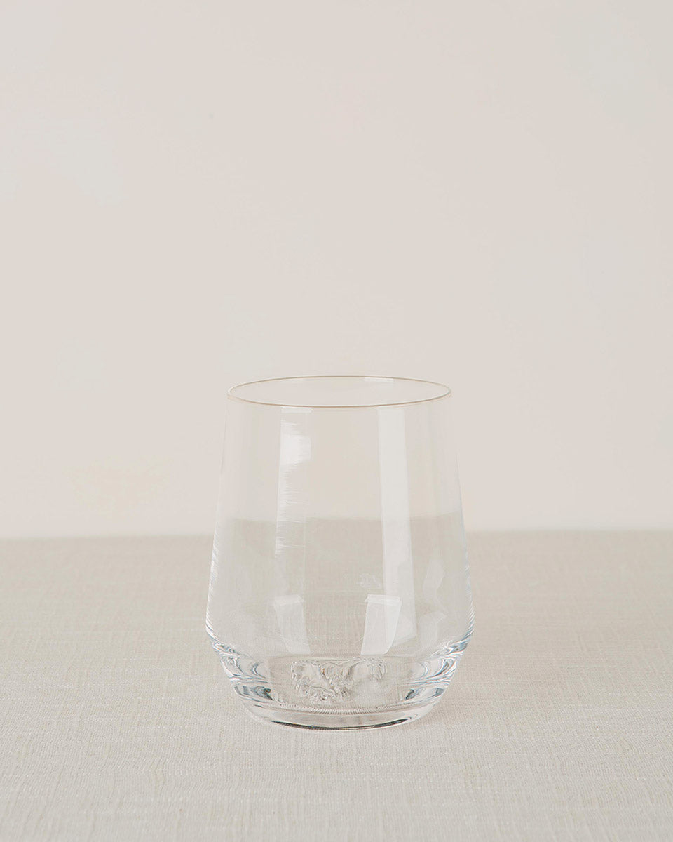 Clear stemless wine glass on a light textured surface with a plain background.